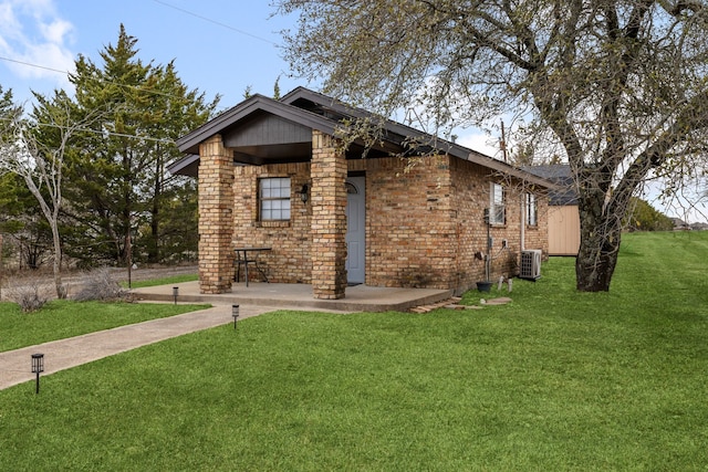 view of front of property with a front yard, central air condition unit, and brick siding