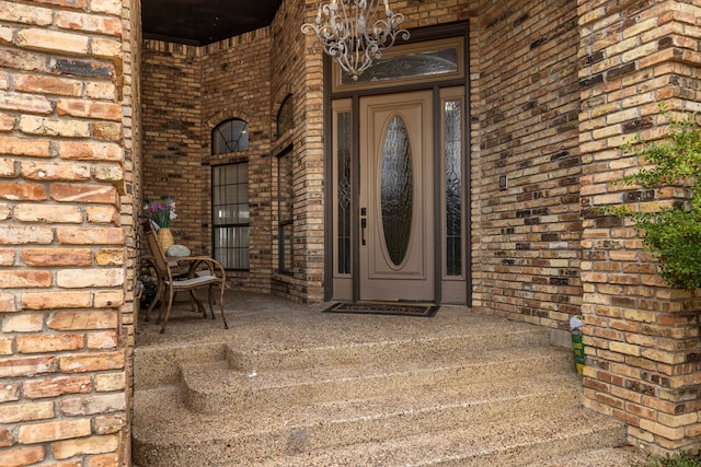 view of exterior entry with brick siding and a porch