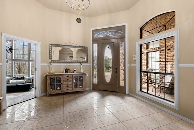 tiled entryway featuring an inviting chandelier, baseboards, and a towering ceiling