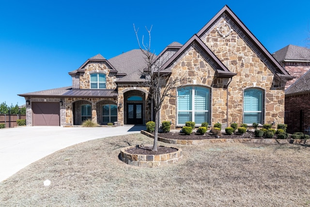 french country inspired facade featuring a standing seam roof, concrete driveway, french doors, a garage, and metal roof