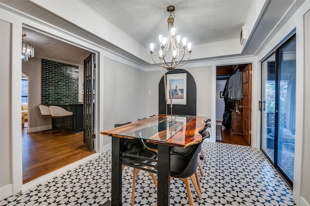 dining space with an inviting chandelier, a tray ceiling, baseboards, and arched walkways