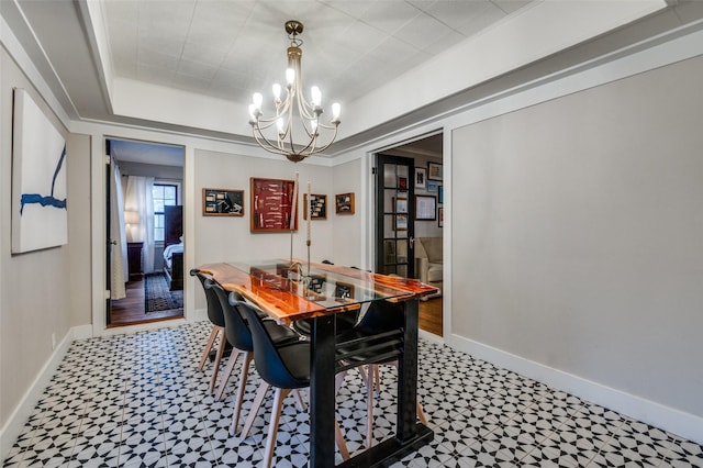 dining space featuring an inviting chandelier, baseboards, crown molding, and a tray ceiling