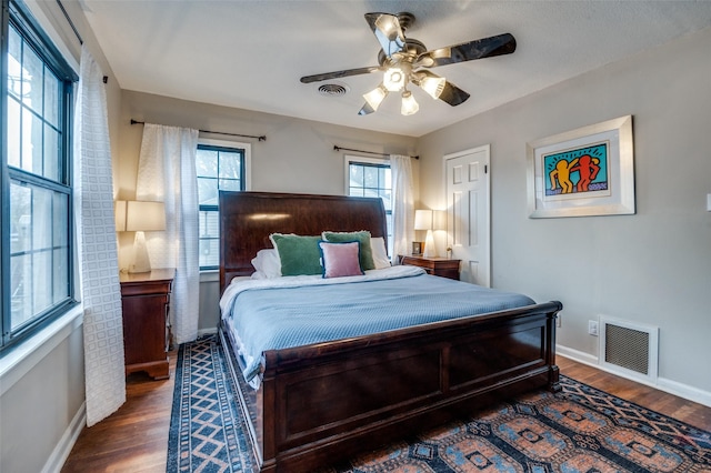 bedroom with ceiling fan, visible vents, baseboards, and wood finished floors