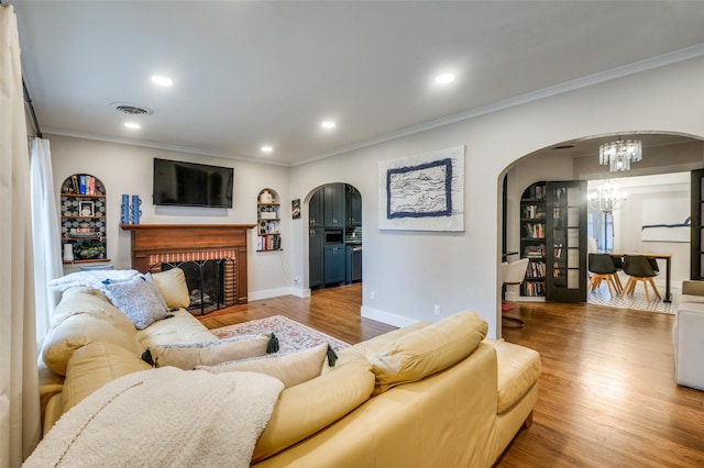 living area with crown molding, a notable chandelier, and arched walkways