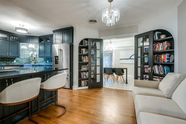 kitchen with visible vents, ornamental molding, light wood-style flooring, high quality fridge, and a chandelier