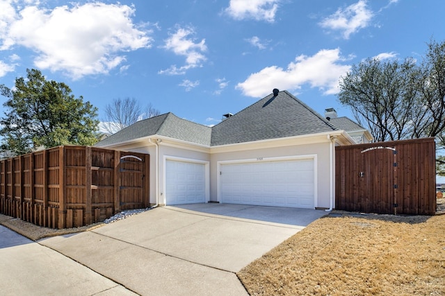 view of front of home with driveway, a gate, fence, roof with shingles, and a garage