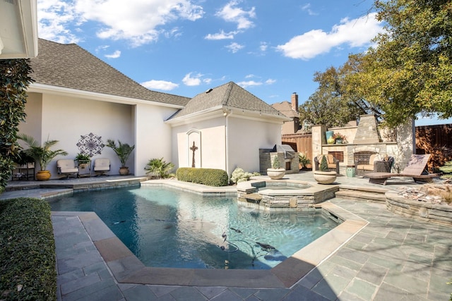 view of pool with a pool with connected hot tub, an outdoor stone fireplace, a patio, and fence