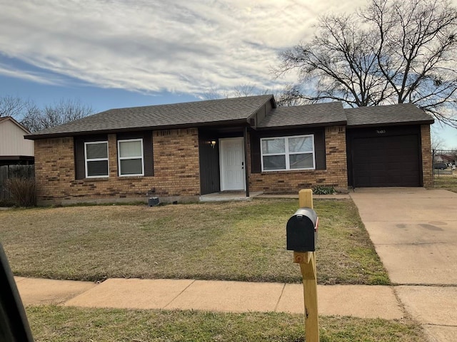 ranch-style home with a shingled roof, concrete driveway, a front yard, an attached garage, and brick siding