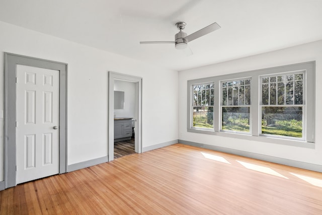 unfurnished bedroom with a ceiling fan, light wood-style floors, baseboards, and connected bathroom