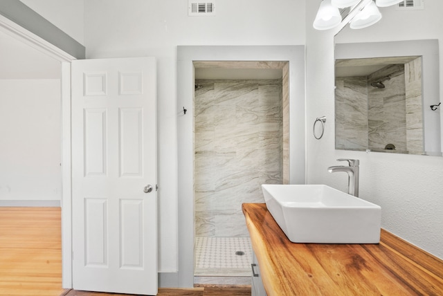 bathroom with a sink, visible vents, and tiled shower