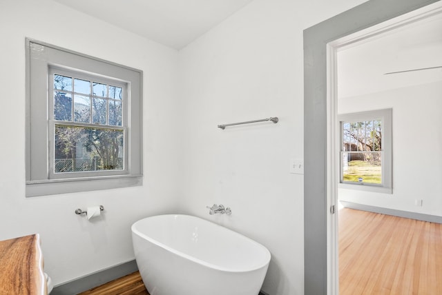 full bath featuring wood finished floors, baseboards, and a freestanding bath