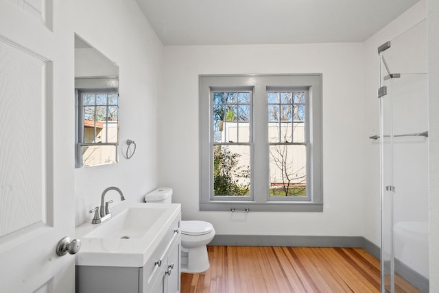 bathroom with vanity, toilet, wood finished floors, and baseboards