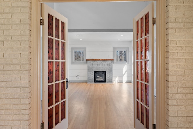 hall featuring brick wall, french doors, and wood finished floors