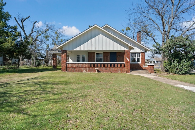 view of front facade featuring brick siding, a chimney, and a front lawn