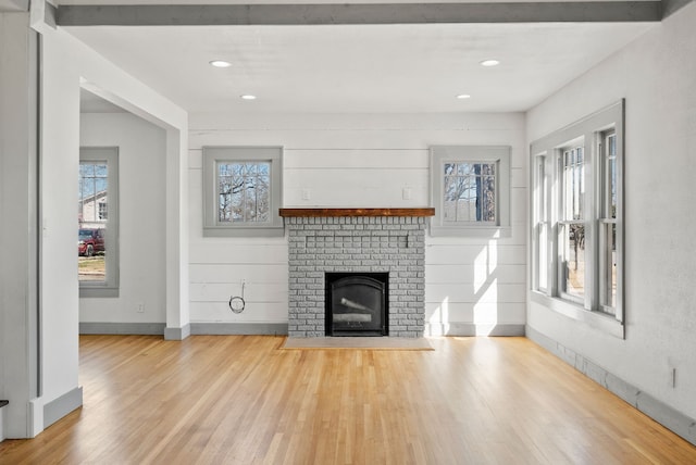 unfurnished living room with a wealth of natural light, a fireplace, baseboards, and wood finished floors