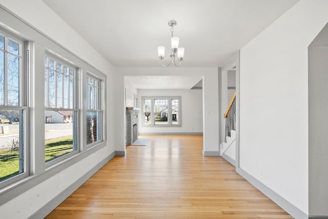 hallway with stairway, baseboards, a notable chandelier, and light wood-style flooring