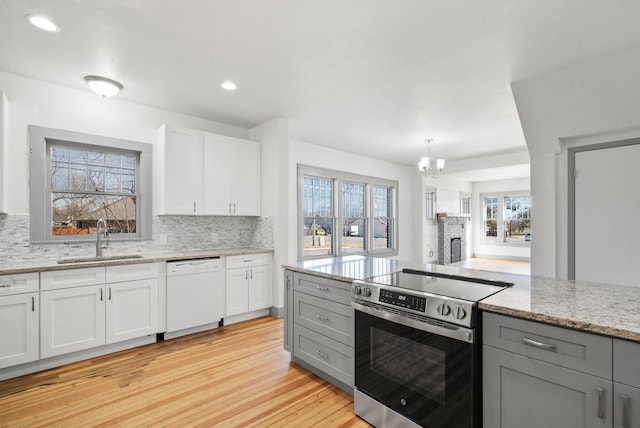 kitchen with a sink, stainless steel range with electric stovetop, gray cabinetry, and white dishwasher