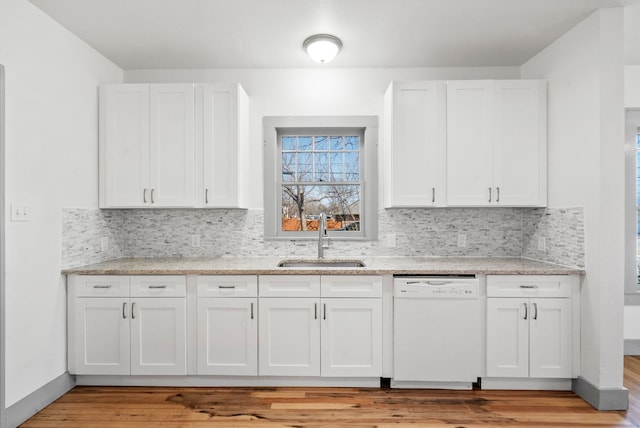 kitchen with white cabinetry, decorative backsplash, white dishwasher, and a sink