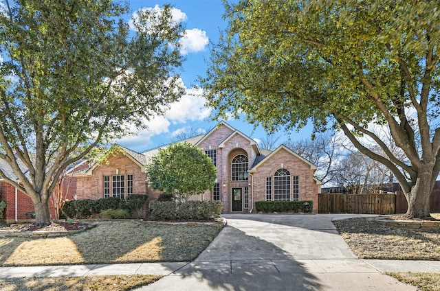 traditional-style home featuring brick siding and fence