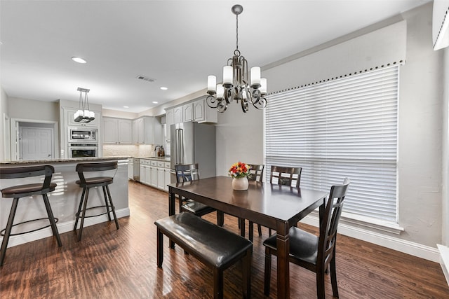 dining space with a chandelier, recessed lighting, dark wood-type flooring, and baseboards