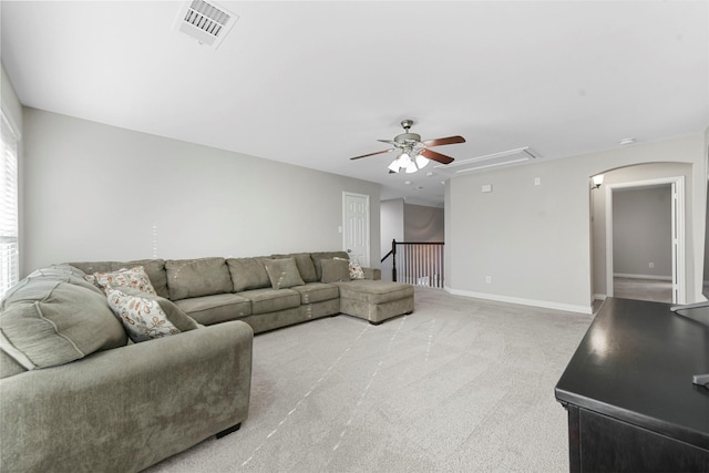 carpeted living area featuring attic access, baseboards, visible vents, and ceiling fan