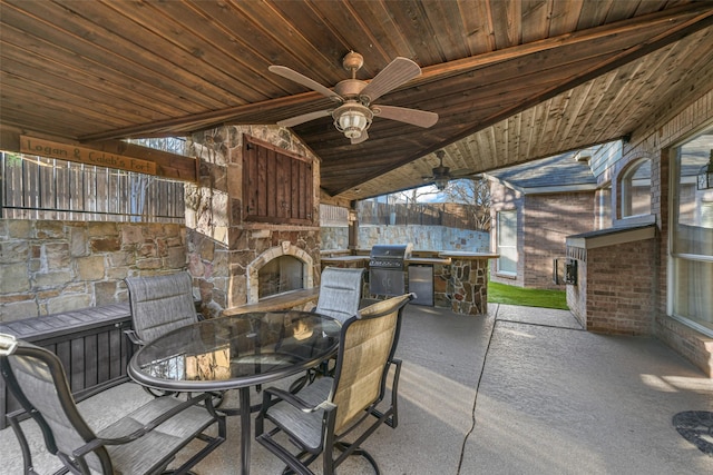 view of patio / terrace featuring a grill, outdoor dining area, a ceiling fan, and an outdoor stone fireplace