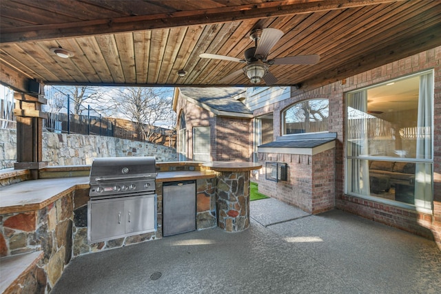 view of patio / terrace featuring an outdoor kitchen, a grill, a ceiling fan, and fence