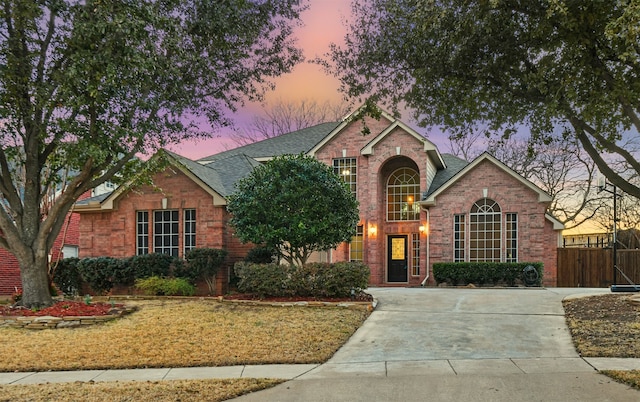 traditional-style house featuring brick siding, a shingled roof, and fence