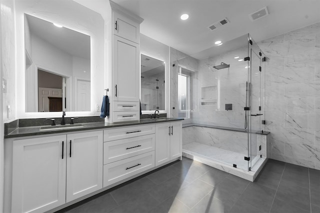 bathroom with a sink, visible vents, and a marble finish shower