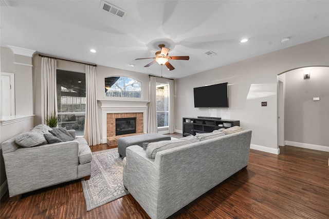 living room featuring wood finished floors, visible vents, arched walkways, and baseboards