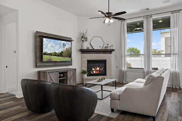living area with visible vents, a brick fireplace, baseboards, ceiling fan, and wood finished floors