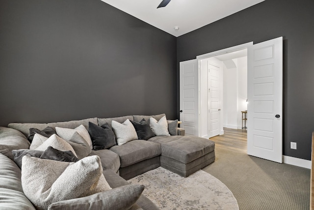 living room featuring baseboards, carpet, and a ceiling fan