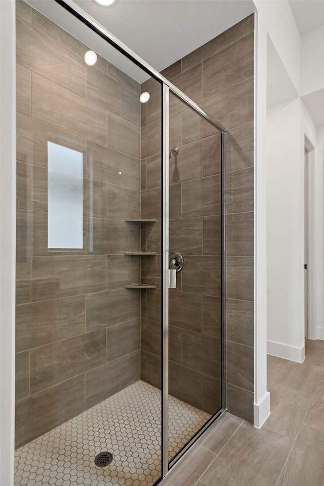 bathroom featuring a shower stall and baseboards