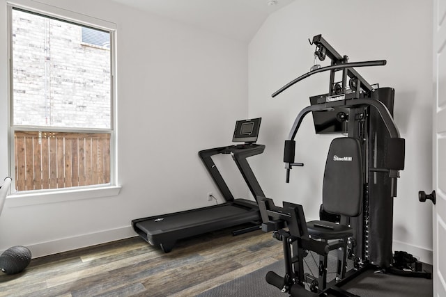 exercise area featuring baseboards, lofted ceiling, and wood finished floors