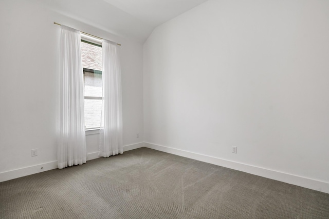 empty room with carpet flooring, baseboards, lofted ceiling, and a wealth of natural light