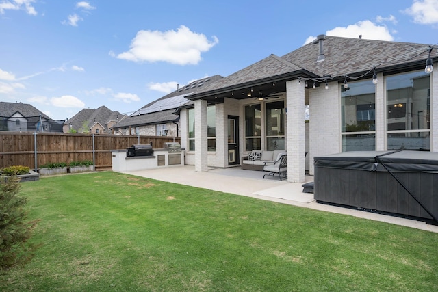 back of house with fence, a hot tub, exterior kitchen, brick siding, and a patio area