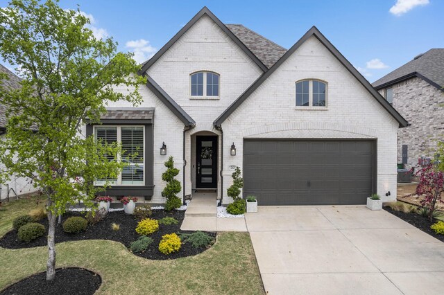 french country home featuring driveway and brick siding