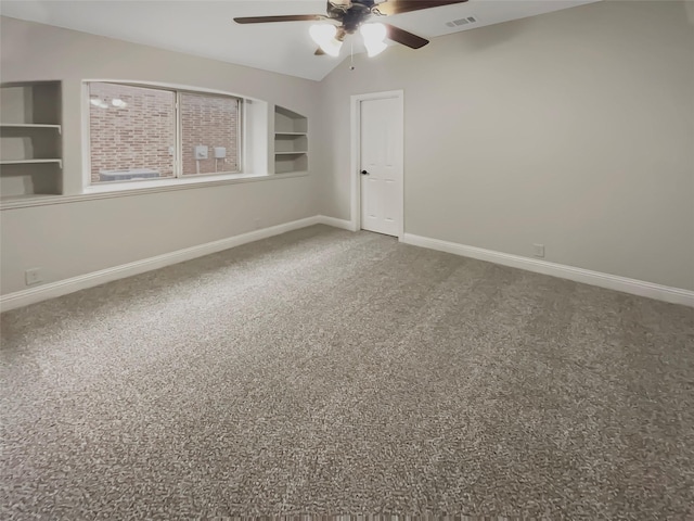 carpeted spare room with a ceiling fan, built in shelves, baseboards, and visible vents