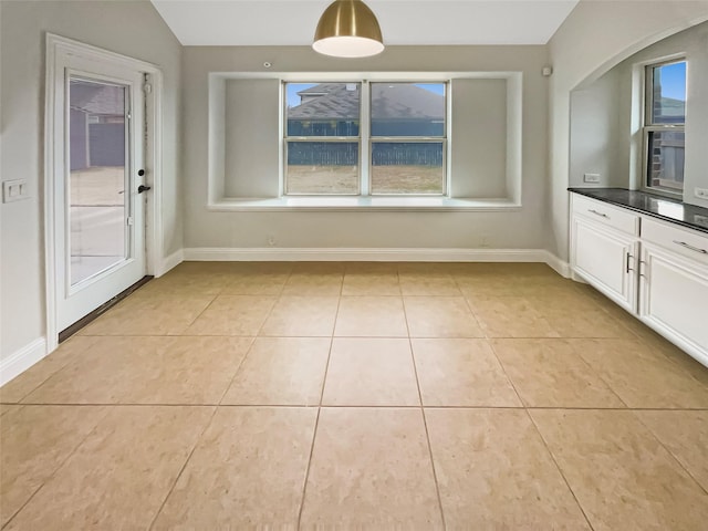 interior space featuring light tile patterned flooring, dark countertops, and baseboards