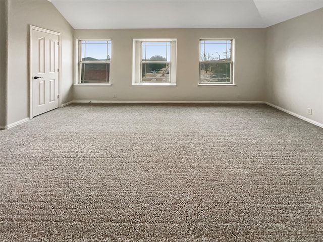 empty room featuring baseboards and vaulted ceiling