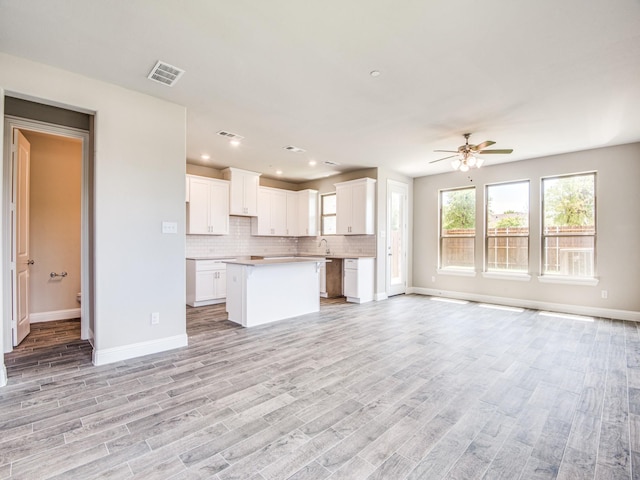 unfurnished living room with a ceiling fan, baseboards, visible vents, light wood-style flooring, and a sink