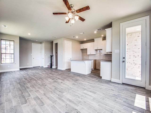 unfurnished living room featuring visible vents, baseboards, and light wood finished floors