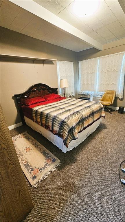 bedroom with beam ceiling, baseboards, and carpet floors