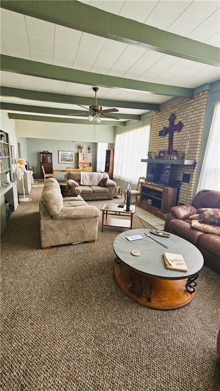 living area with beam ceiling, carpet flooring, and a ceiling fan