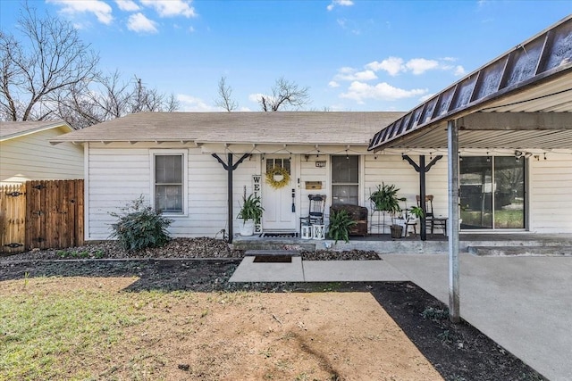 single story home featuring roof with shingles, fence, and covered porch