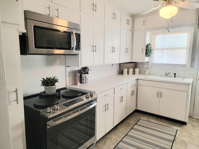 kitchen with a sink, stainless steel appliances, light countertops, backsplash, and white cabinetry