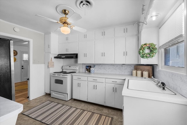 kitchen with electric range, freestanding refrigerator, light countertops, white cabinets, and under cabinet range hood