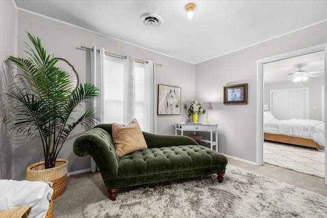 living area featuring visible vents, baseboards, ceiling fan, crown molding, and carpet floors