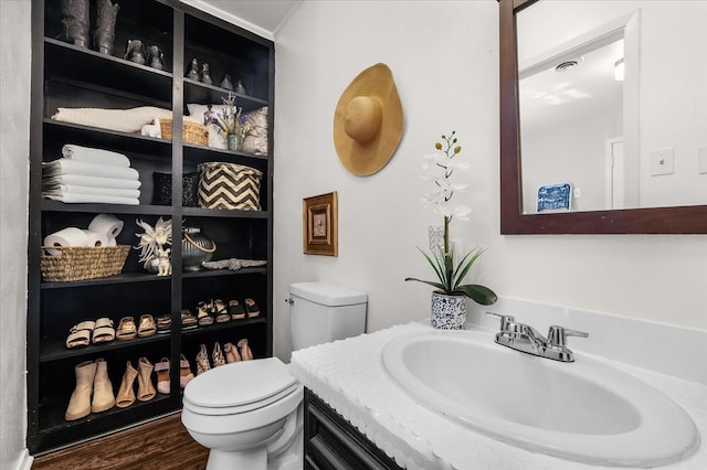 bathroom with toilet, wood finished floors, and vanity