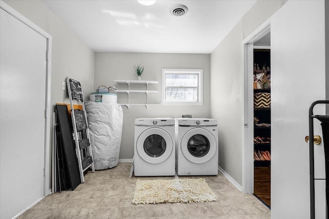 washroom featuring water heater, laundry area, visible vents, baseboards, and washer and dryer